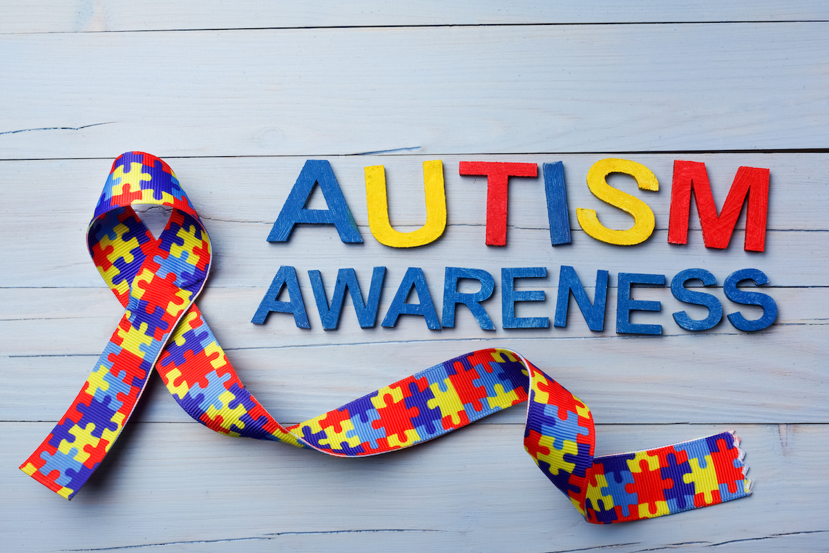 World Autism awareness and pride day or month with Puzzle pattern ribbon on wooden background.